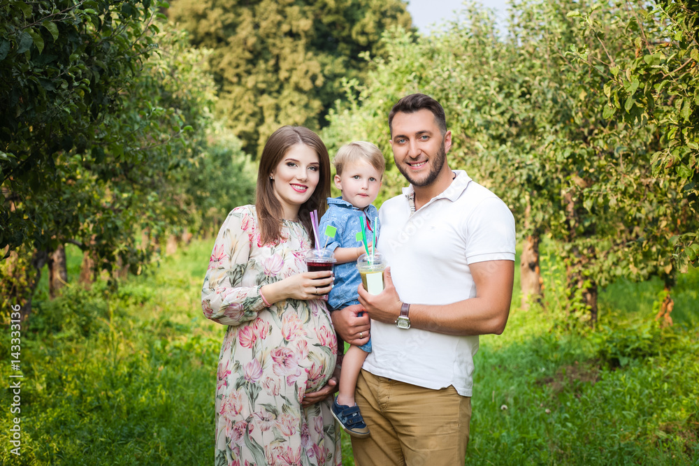 Fototapeta premium Young attractive family walking in a meadow and drinking juice