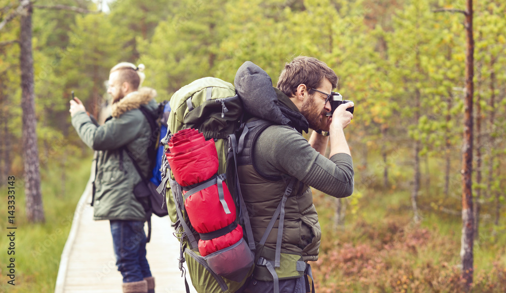 Two guys with backpacks walking in swamps and taking pictures. Camp, adventure, traveling and fishing concept. Two guys with backpacks walking in swamps and taking pictures. Camp, adventure, traveling and fishing concept.