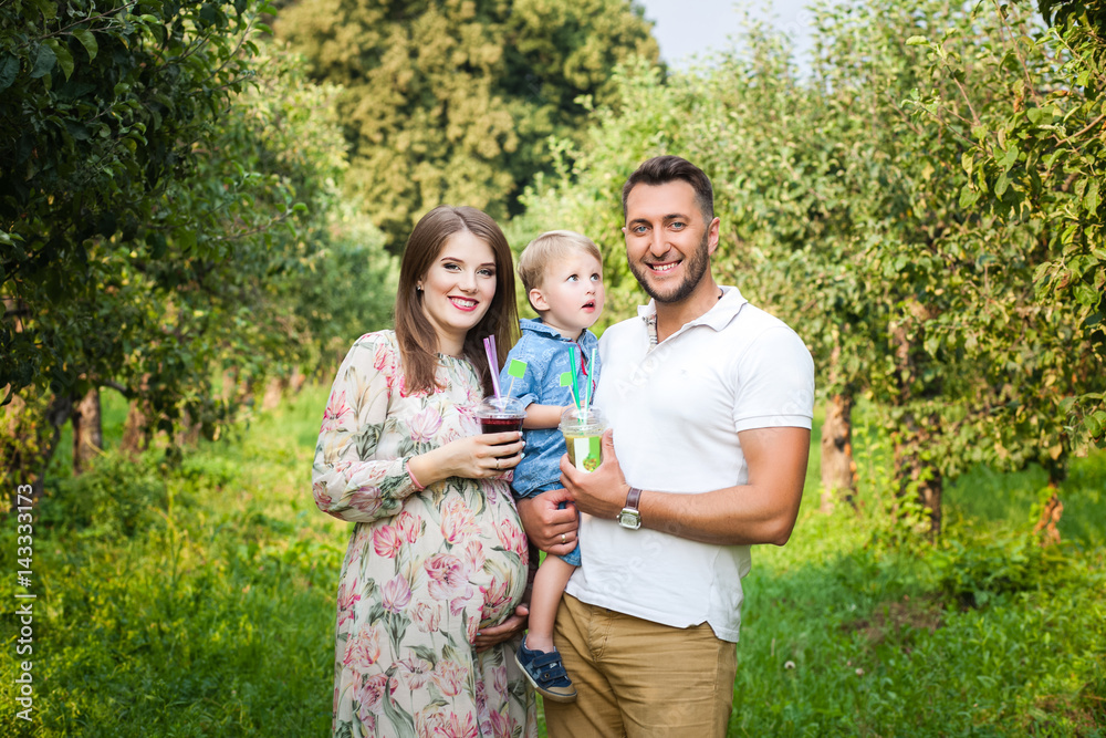 Fototapeta premium Young attractive family walking in a meadow and drinking juice