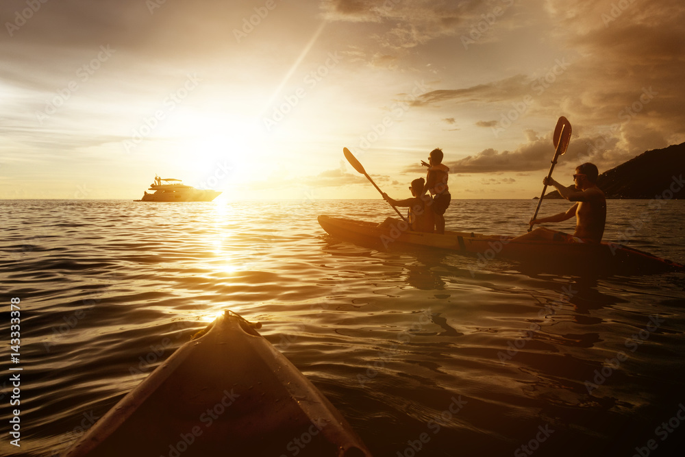 Two kayaks with family at sunset sea
