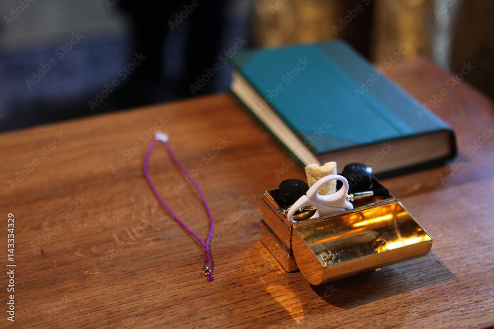 The prayer book, the orthodox cross and the box with the chrism during the Baptismal ceremony The prayer book, the orthodox cross and the box with the chrism during the Baptismal ceremony