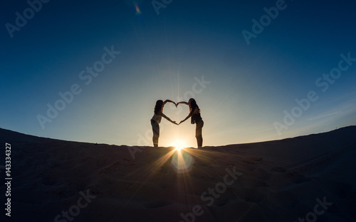 Friendship, heart of two people above the sun