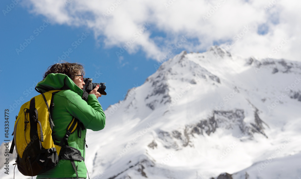 Hiker with camera and backpack taking picture of beautiful mountain