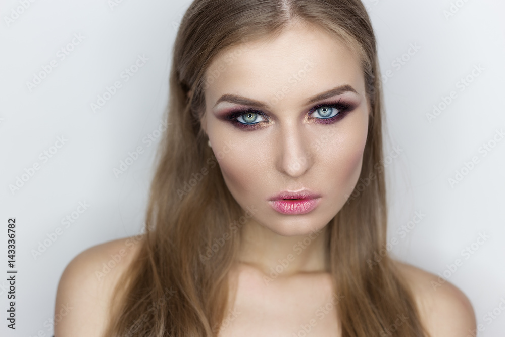 Fashionable portrait of a beautiful sexy girl with crazy hairstyle with bright colored makeup with bared shoulders in the studio on a white background Fashionable portrait of a beautiful sexy girl with crazy hairstyle with bright colored makeup with bared shoulders in the studio on a white background
