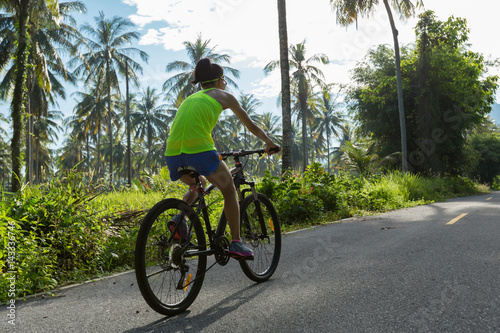 Young woman cycling on tropical forest trail