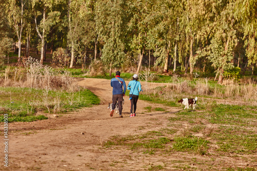 Ganey Aviv - 02 December 2016: A couple walks with their dogs in the field, near Ganey Aviv, Israel photo