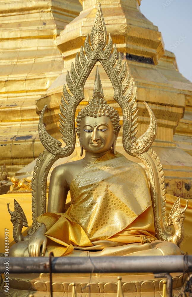 Front of sitting Thai Buddha statue that wear golden clothes.