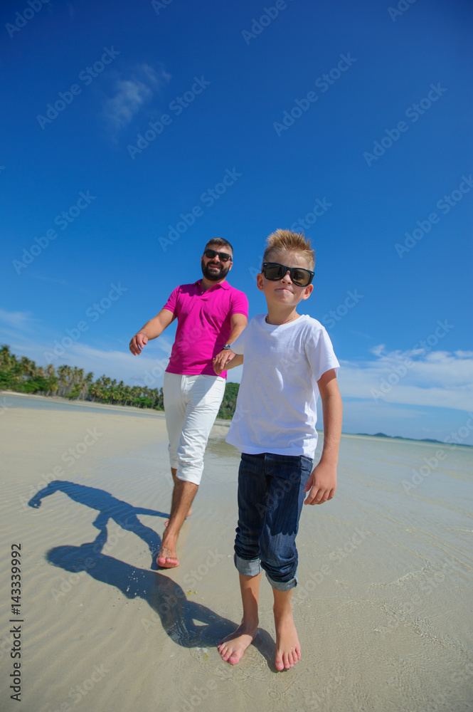 Father and son running along the tropical beach