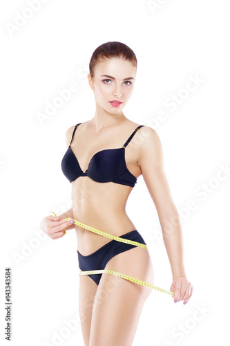 Fit, healthy and sporty woman in black swimsuit isolated on white. Beautiful girl measuring her body. Sport, fitness, diet, weight loss and healthcare concept. © Acronym