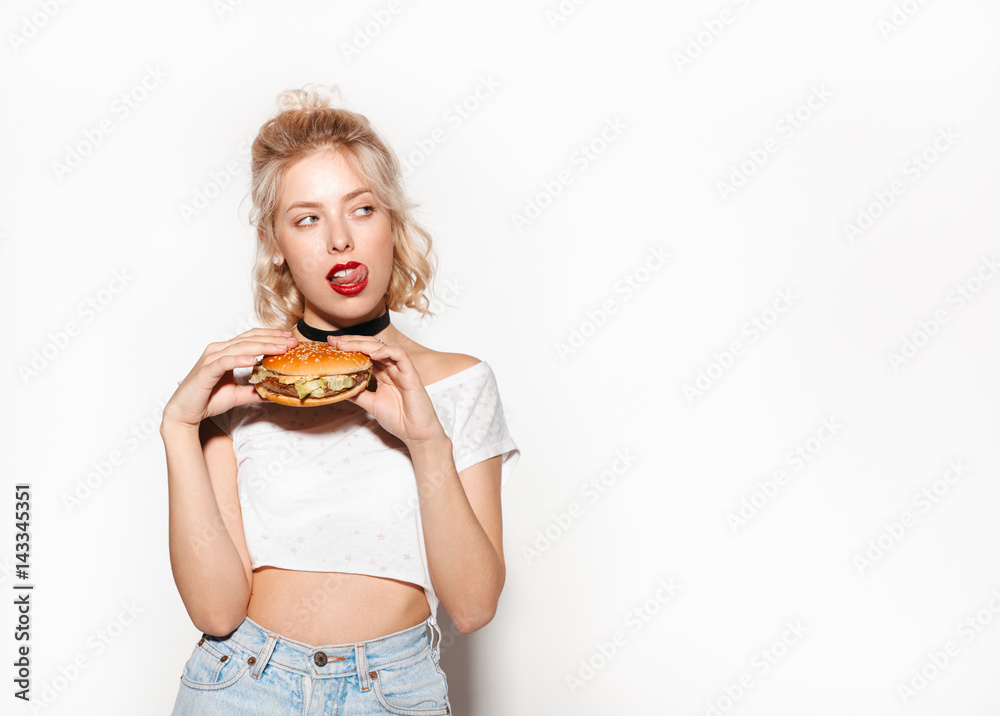 Woman holding burger and licking lips Woman holding burger and licking lips