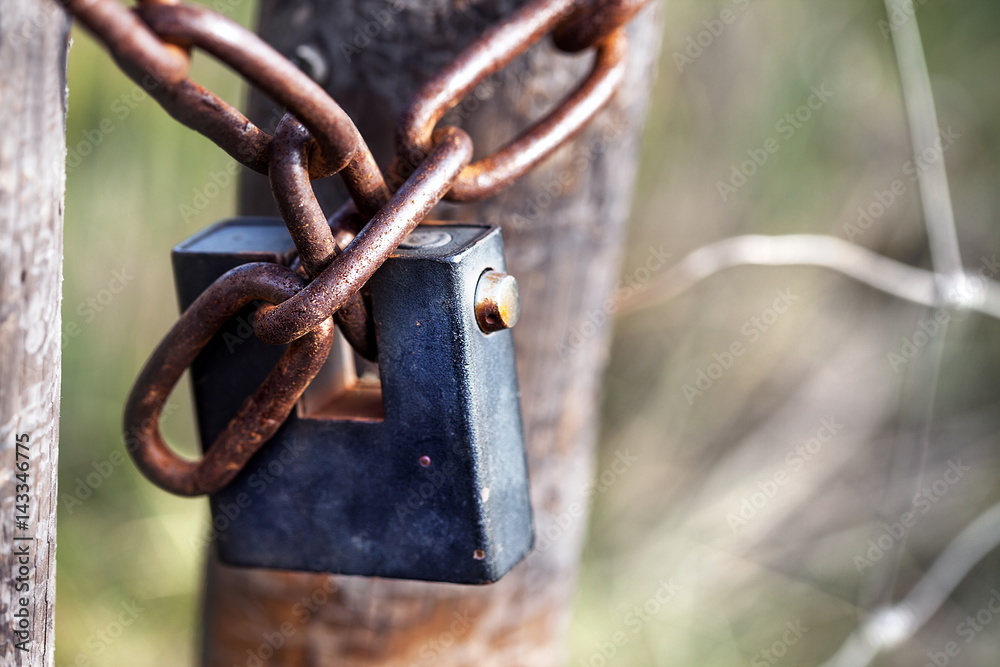 Old padlock and rusty chain on a rural pasture wooden gate Old padlock and rusty chain on a rural pasture wooden gate