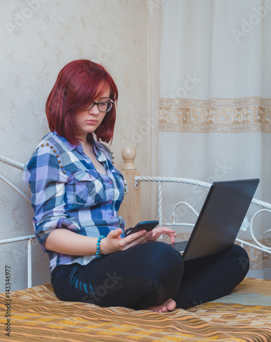 Young Woman with Red Hair Working from Home - Female Entrepreneur Sitting on Bed with Laptop Computer,