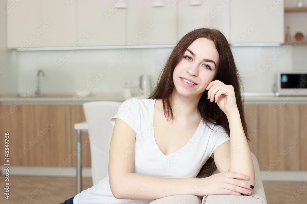 Smiling woman which sitting on kitchen and looking at camera. Smiling woman which sitting on kitchen and looking at camera.