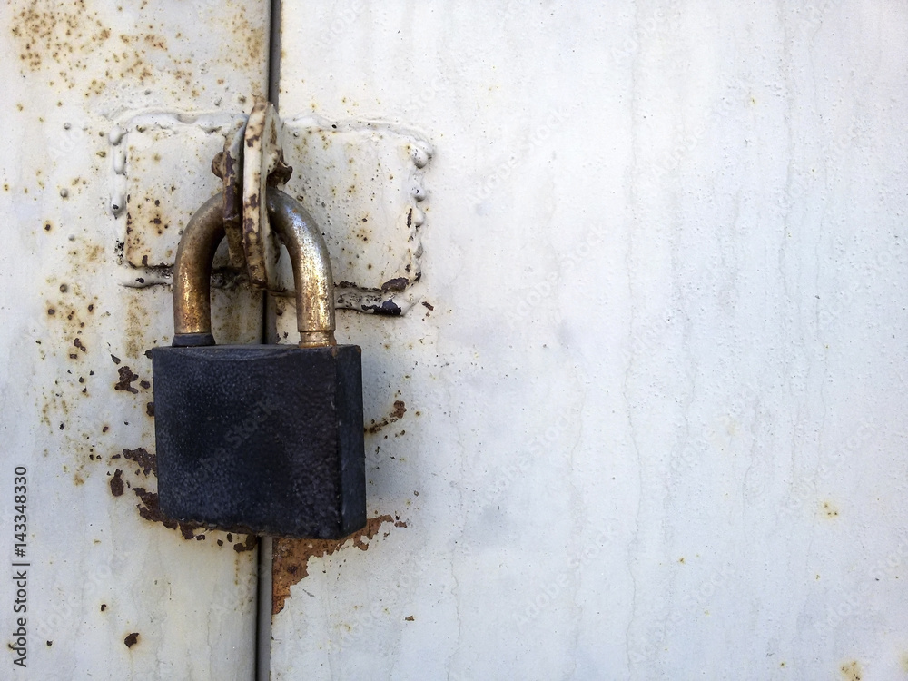 Padlock on the rusty gray wall of the garage Padlock on the rusty gray wall of the garage