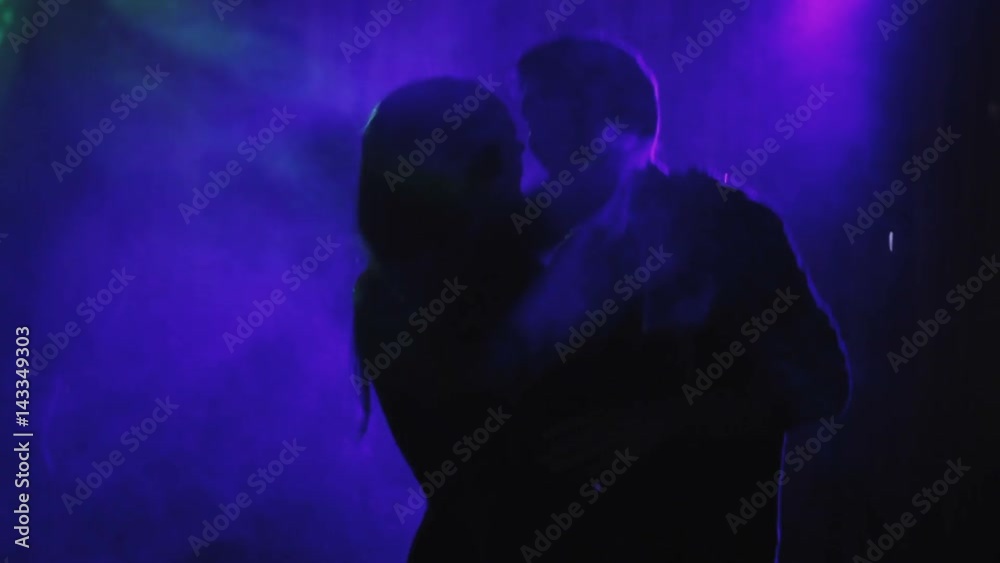 A couple of people, a girl and a guy are dancing at a disco. Silhouette of people in dance. A couple of people, a girl and a guy are dancing at a disco. Silhouette of people in dance.