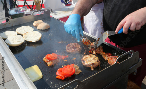 Принти на полотні On the stand of street food there is a chef with blue gloves coo