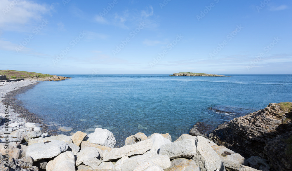 Rocky coastline at Moelfre, Anglesey in North Wales with distant view of Moelfre Island (Ynys Moelfre)