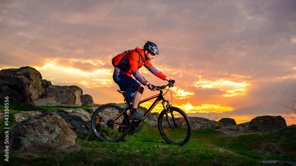 Cyclist Riding Mountain Bike on the Spring Rocky Trail at Beautiful Sunset. Extreme Sports and Adventure Concept. Cyclist Riding Mountain Bike on the Spring Rocky Trail at Beautiful Sunset. Extreme Sports and Adventure Concept.