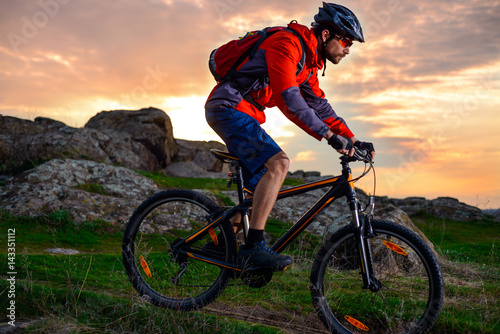 Cyclist Riding Mountain Bike on the Spring Rocky Trail at Beautiful Sunset. Extreme Sports and Adventure Concept.