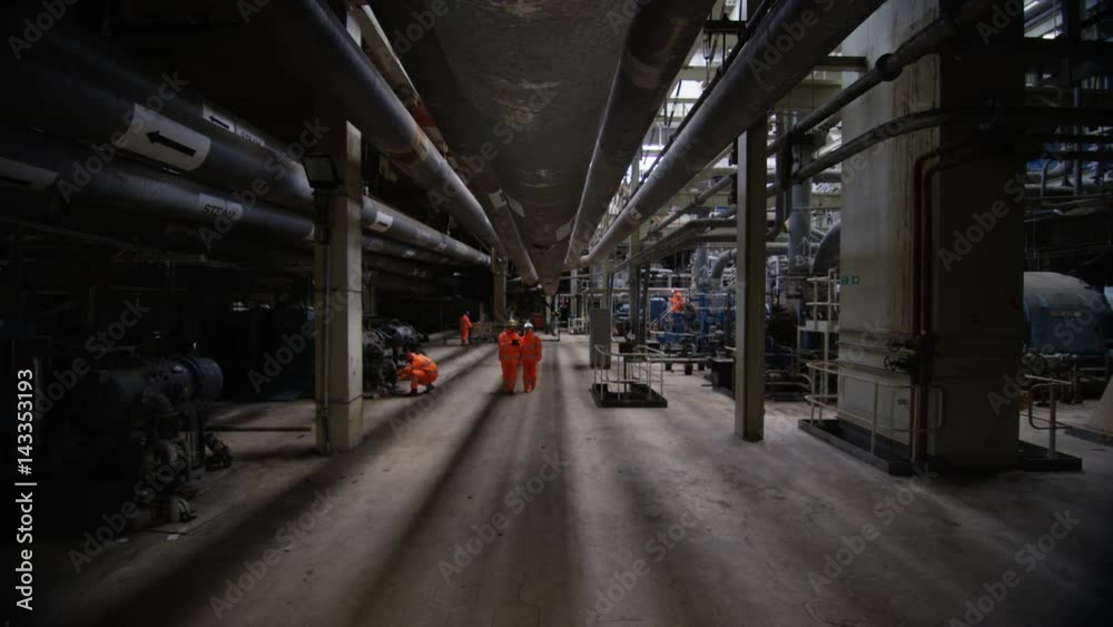 Team of engineers in power station, wide shot of workers & interior structure Team of engineers in power station, wide shot of workers & interior structure
