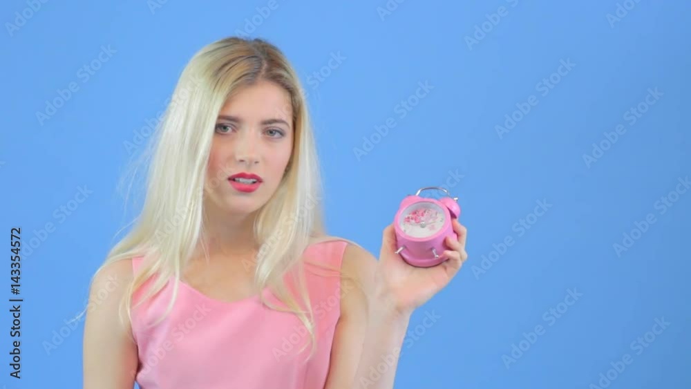 Attractive sad yong woman holds an alarm clock Attractive sad yong woman holds an alarm clock
