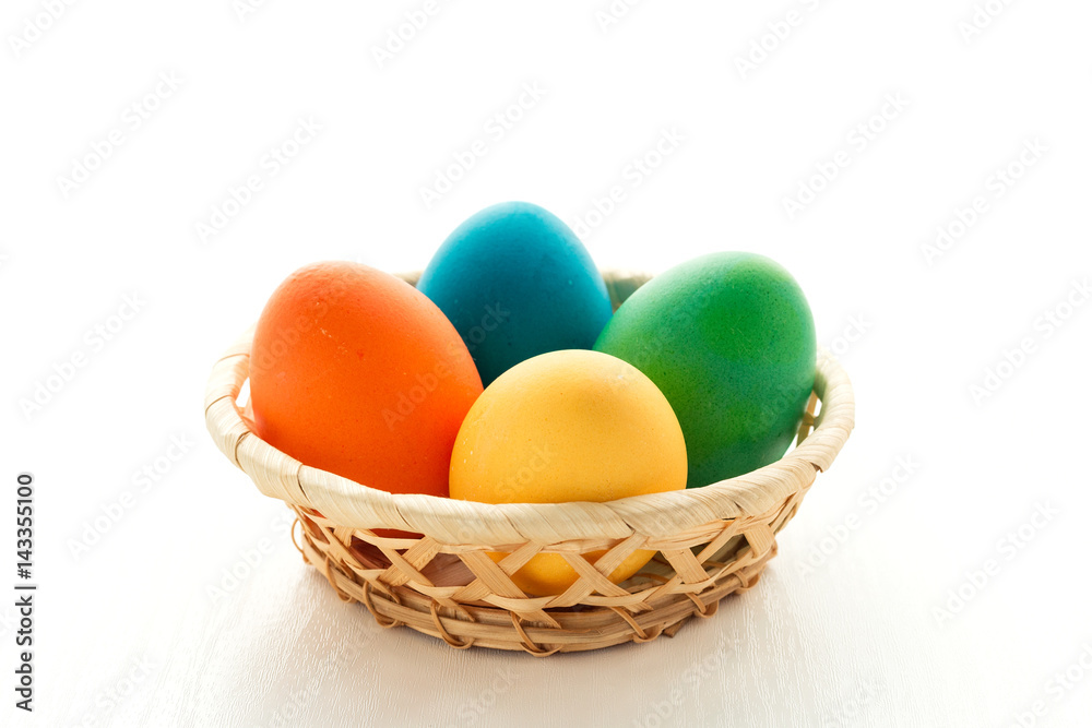 Multicolored easter eggs in a basket, on a white wooden background. The concept of a holiday and a happy Easter. With space for text Multicolored easter eggs in a basket, on a white wooden background. The concept of a holiday and a happy Easter. With space for text