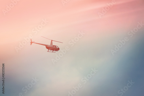 Helicopter flying in the blue sky with sunlight