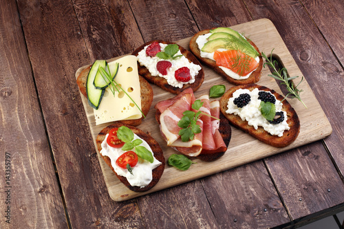 Bread Brushetta or authentic traditional spanish tapas set for lunch table. Sharing antipasti on party or summer picnic time over wooden rustic background.