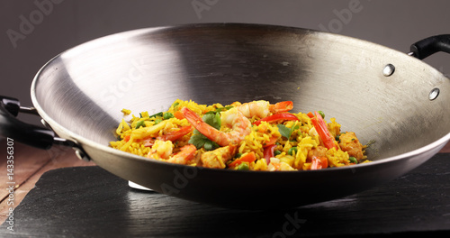 Udon stir-fry rice with shrimp and vegetables in wok pan on black burned stone background