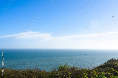 Coastguard helicopter and a flock of birds over the English Channel, UK