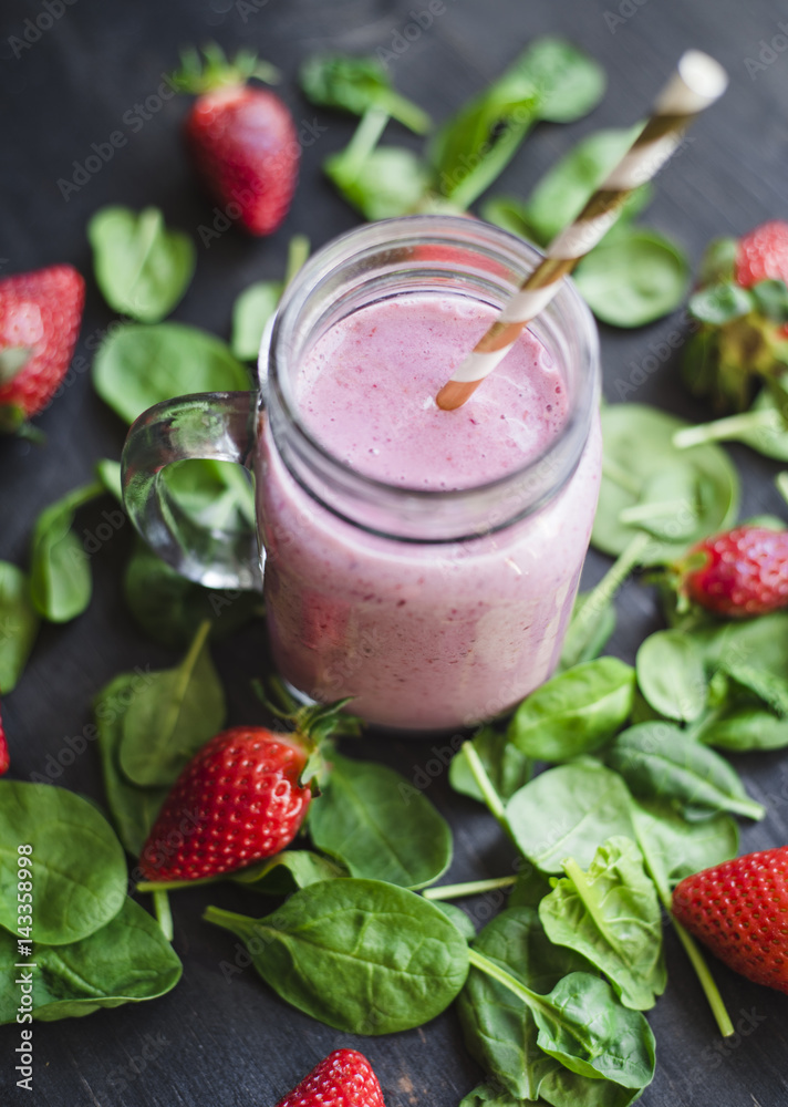 Strawberry green smoothie in a glass jar on a dark wooden table Strawberry green smoothie in a glass jar on a dark wooden table
