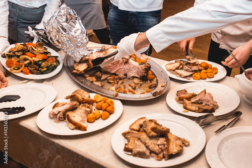 chef cuts roasted meat for restaurant guests