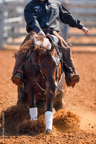 A front view of western rider sliding the horse in the dirt