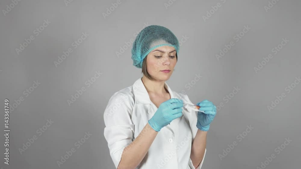 Young female doctor in gloves holding a syringe isolated on grey background. Healthcare concept. Shot in 4k Young female doctor in gloves holding a syringe isolated on grey background. Healthcare concept. Shot in 4k