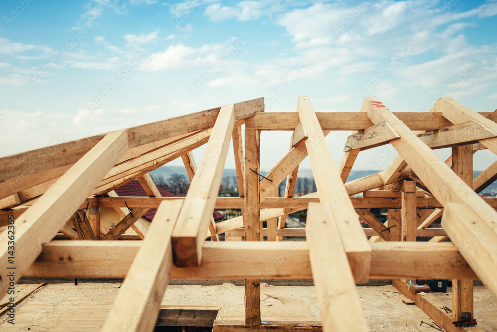 Installation of wooden beams and timber at construction site. Building the roof truss system structure of new residential house Installation of wooden beams and timber at construction site. Building the roof truss system structure of new residential house