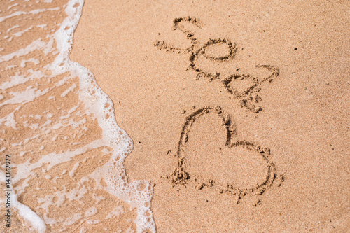 Sea and heart in the sand on the beach photo