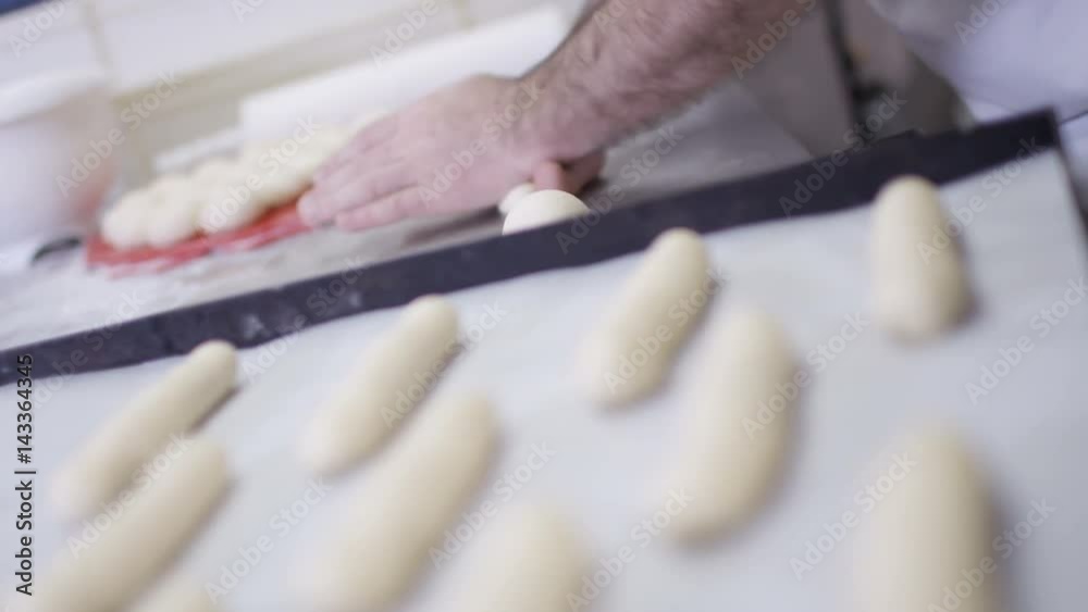 Close up on hands, man rolling out balls of dough in a bakery shop Close up on hands, man rolling out balls of dough in a bakery shop