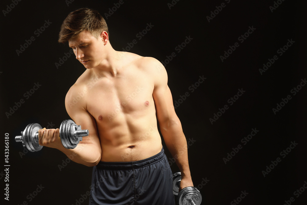 Young handsome sportsman with dumbbells on dark background Young handsome sportsman with dumbbells on dark background