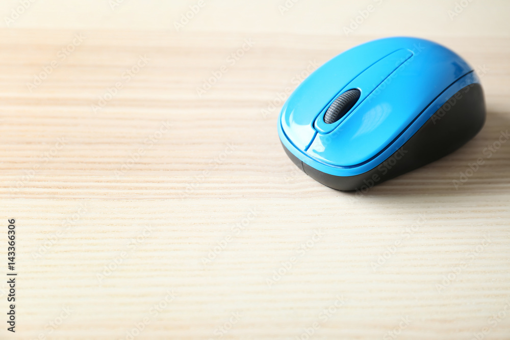 Blue wireless mouse on light wooden table Blue wireless mouse on light wooden table