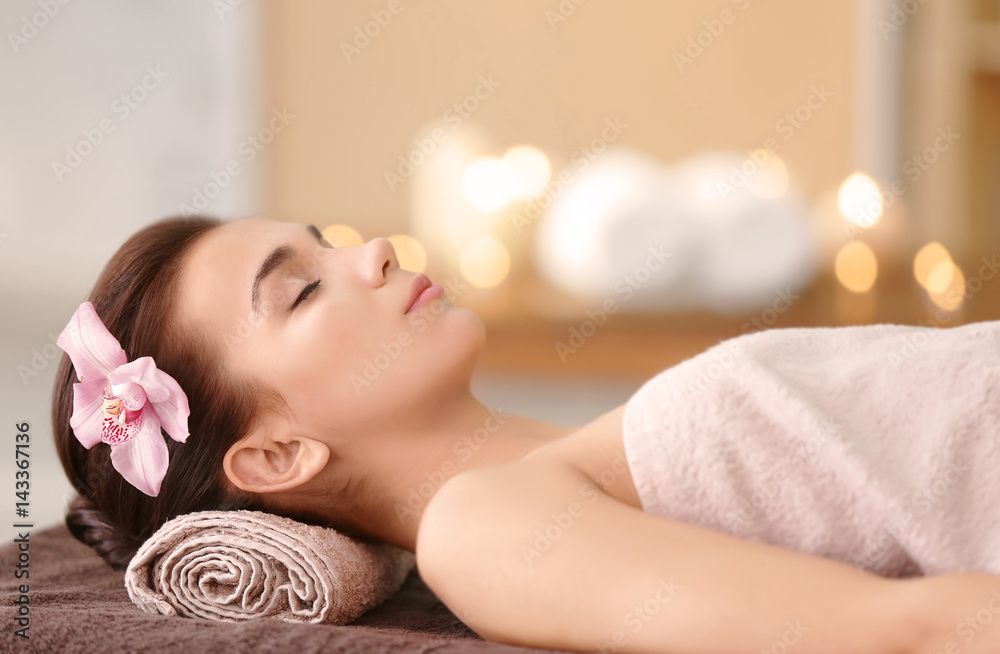 Beautiful young woman lying on massage table in spa salon