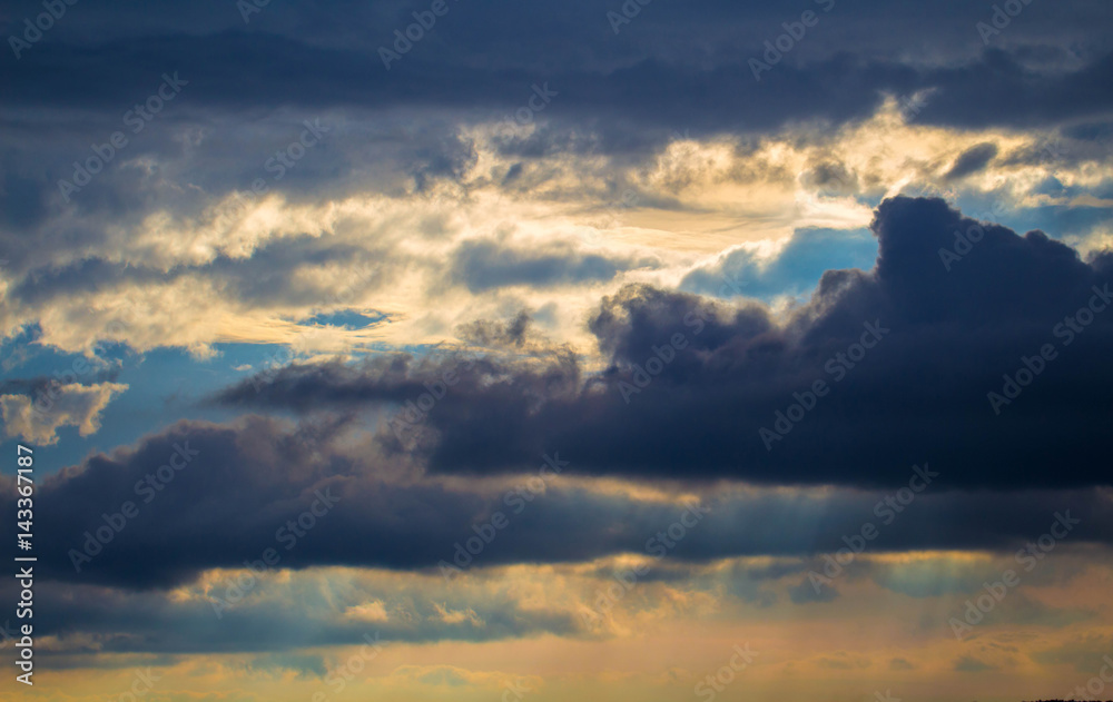 Stormy sky with rays of sunlight. Sunset scene with rainy clouds.