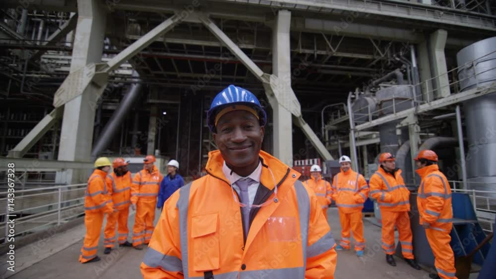  Portrait smiling manager at industrial plant with team of workers behind him