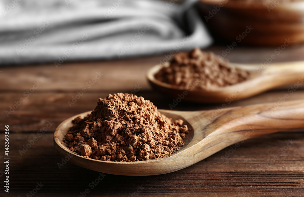 Two spoons with cocoa powder on wooden background Two spoons with cocoa powder on wooden background