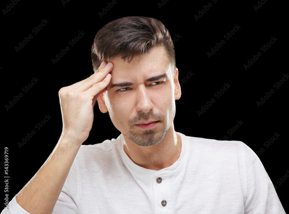 Handsome young man suffering from headache on black background Handsome young man suffering from headache on black background