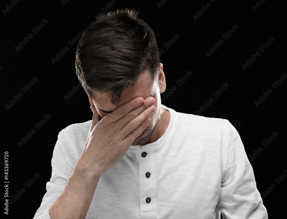 Handsome young man suffering from headache on black background Handsome young man suffering from headache on black background