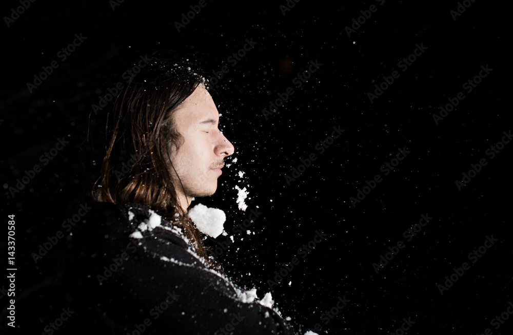 The man in whose face flying snow. Black background.