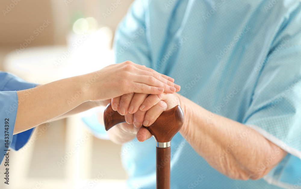 Φωτογραφία Young doctor holding hands of elderly woman on light background, closeup
