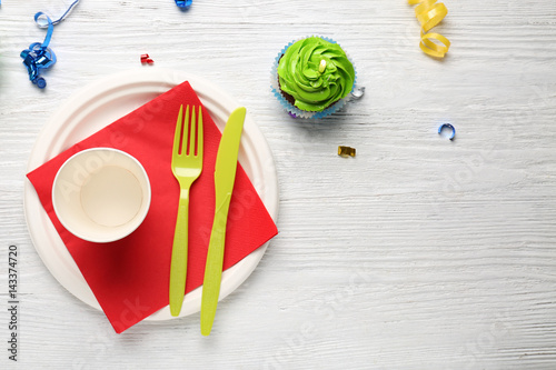 Plate with birthday cupcake and cup on wooden table