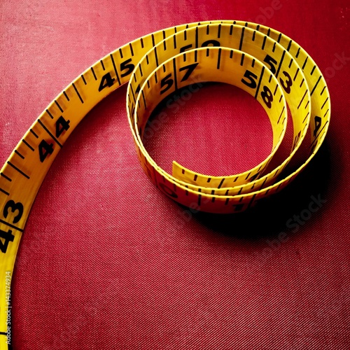 Tape measure coiled on red background