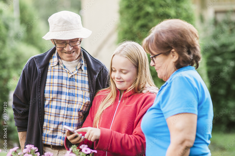 Sweden, Vastmanland, Hallefors, Bergslagen, Girl (12-13) with grandparents looking at phone display Sweden, Vastmanland, Hallefors, Bergslagen, Girl (12-13) with grandparents looking at phone display